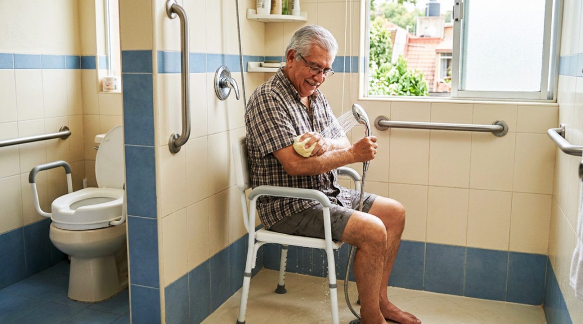 Silla para ducha con respaldo, descansabrazos y orificios de drenaje para adulto mayor.