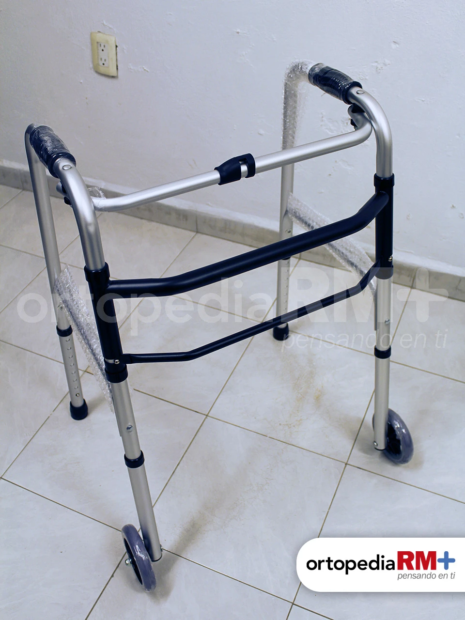 Andadera ortopédica plegable con dos ruedas delanteras y regatones traseros para estabilidad.